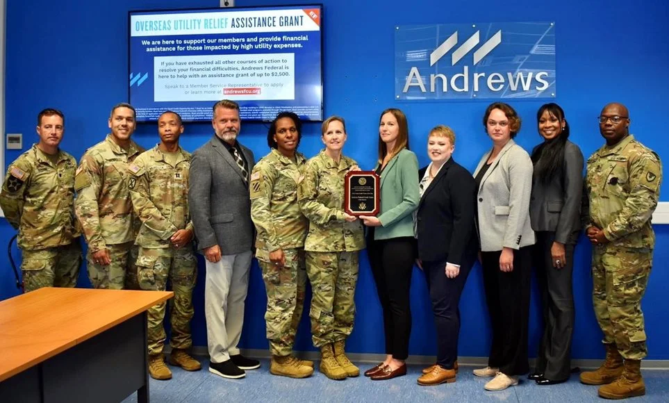 Member of the military and members of team Andrews standing and holding an award