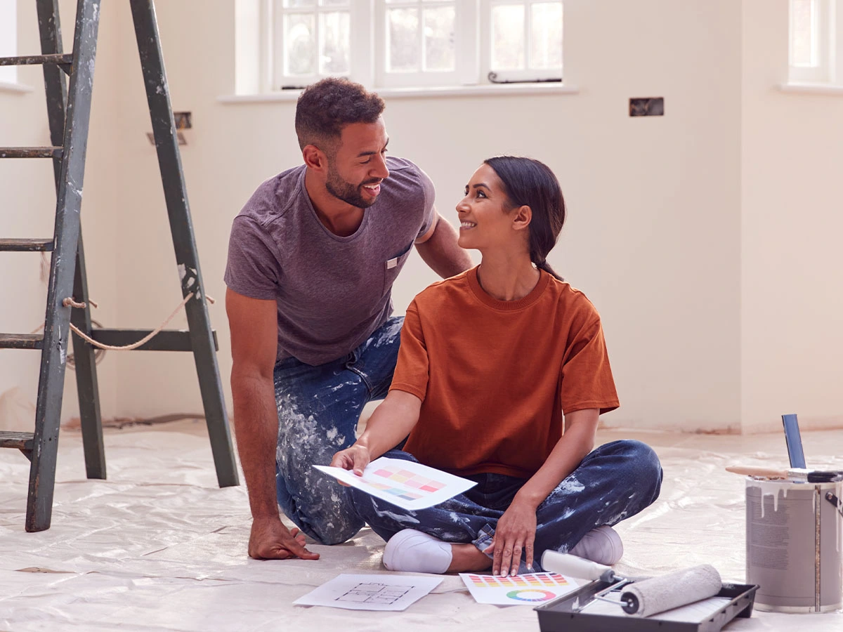 Couple sitting on floor with painting supplies