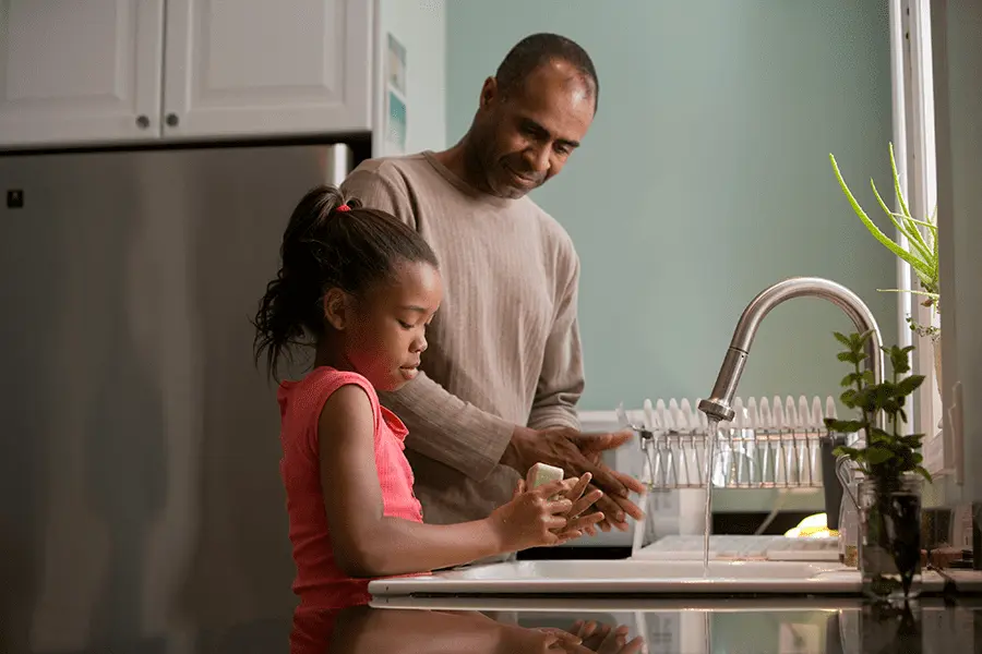 Father and daughter washing their hands in the kitchen