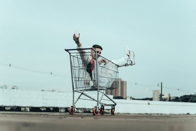 Man Sitting in a shopping cart in an open lot