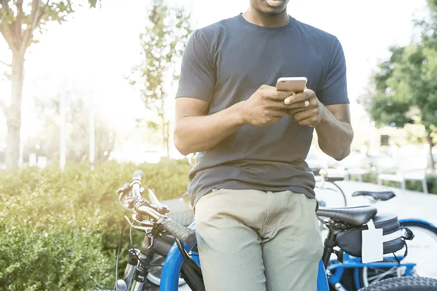 Man leaning on bike texting