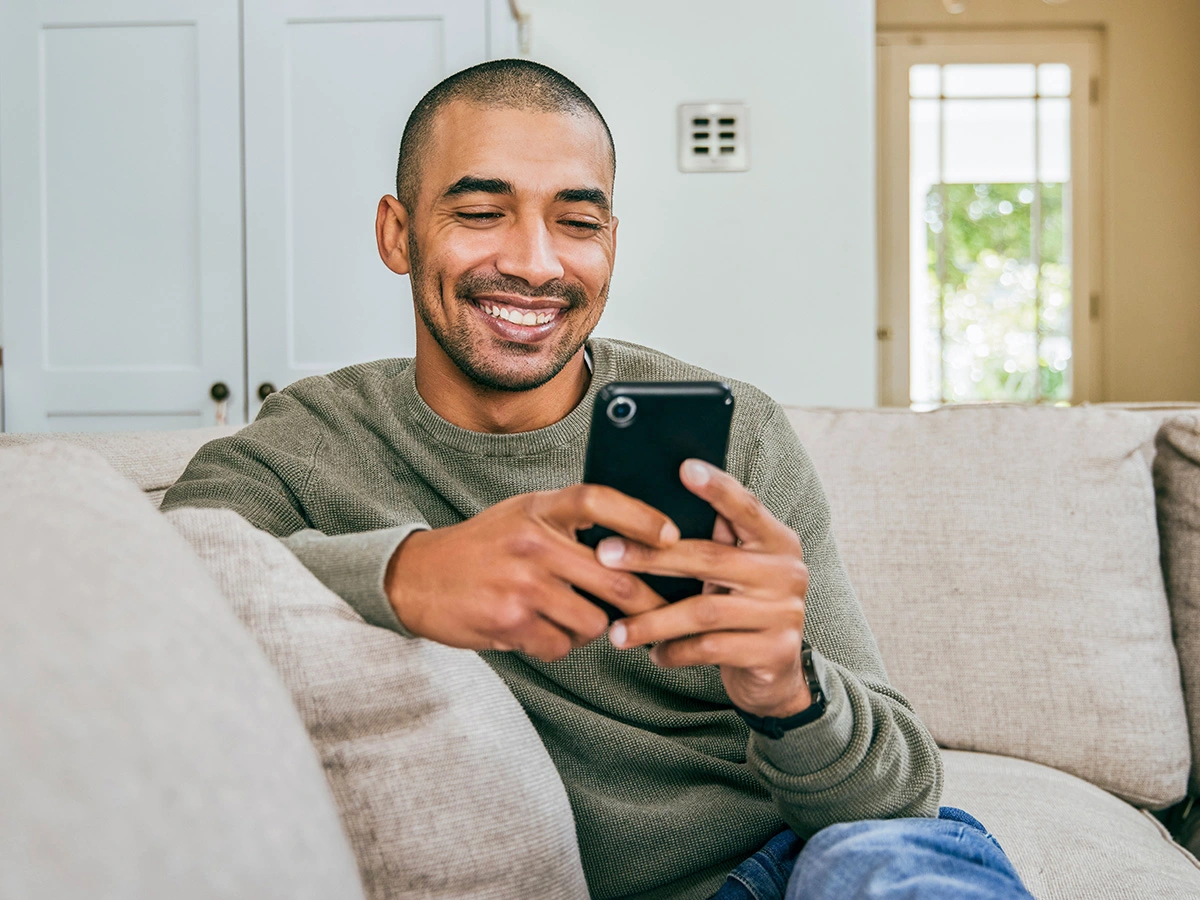 Man on couch smiling down at his phone