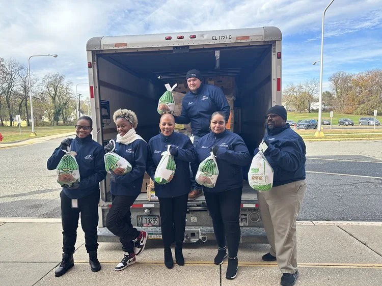 Andrews team members holding donated turkeys in front of donation truck