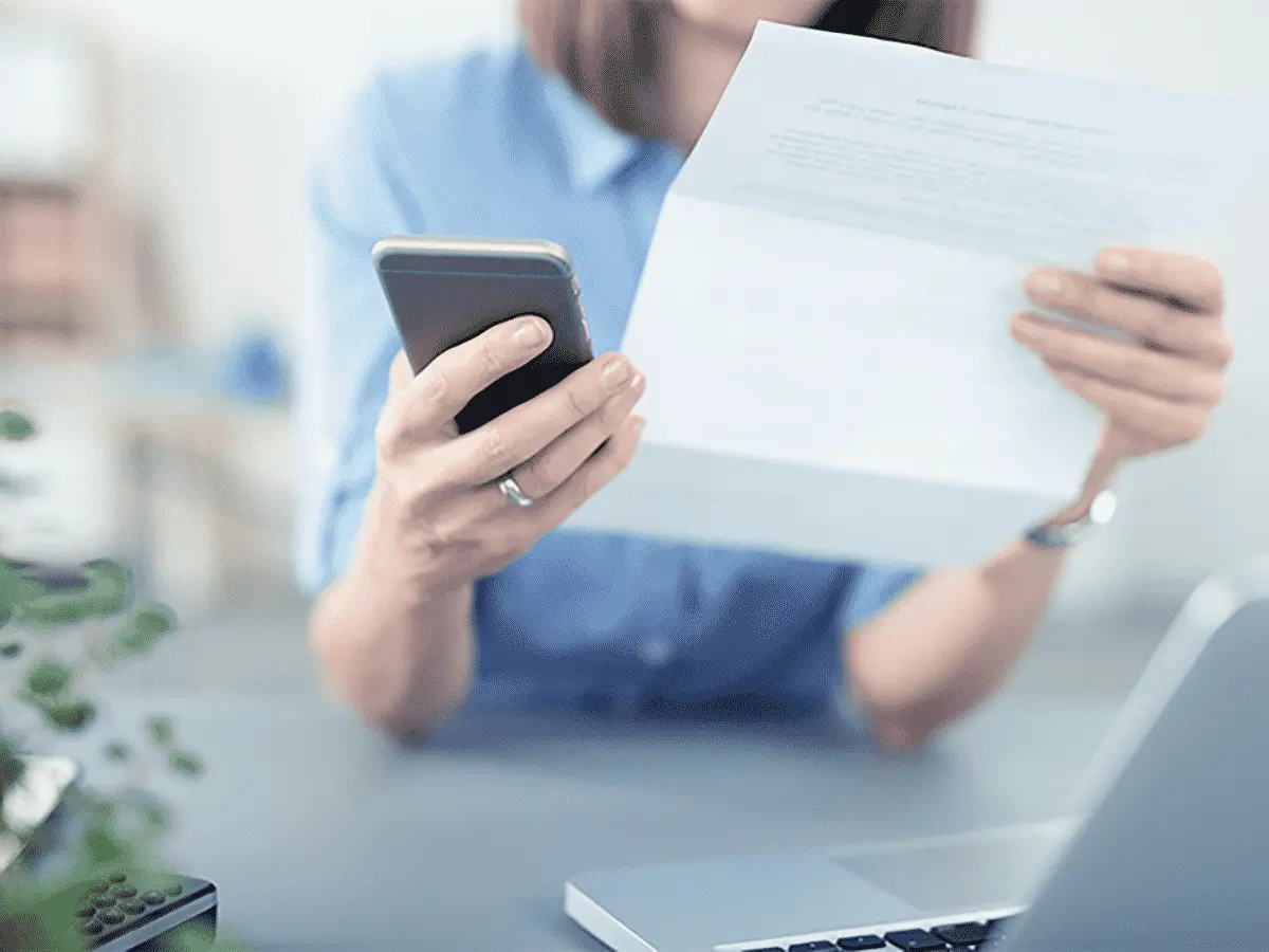 Woman holding a bill and cell phone