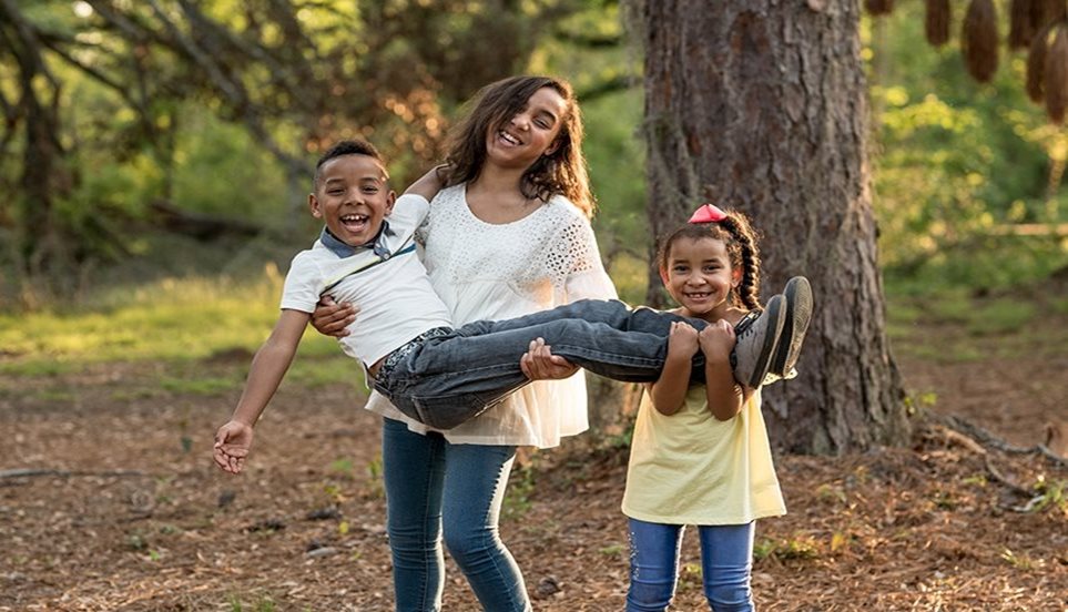 Mother and daughter holding up brother outside