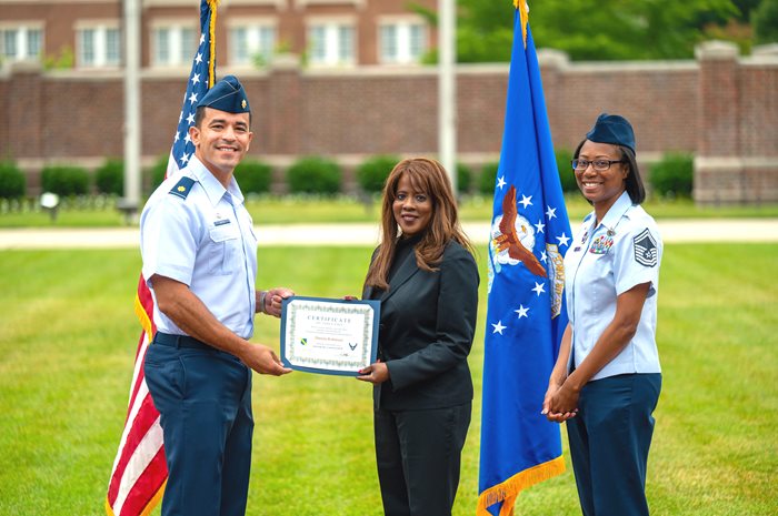 COO Robinson accepting award with two military members