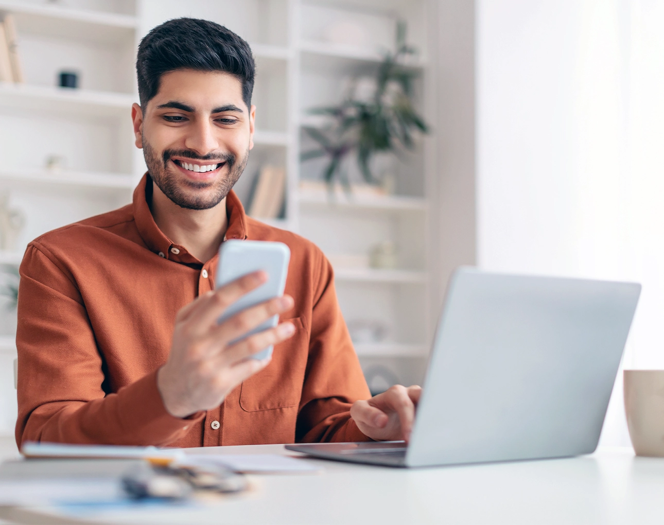happy man checking phone and using computer