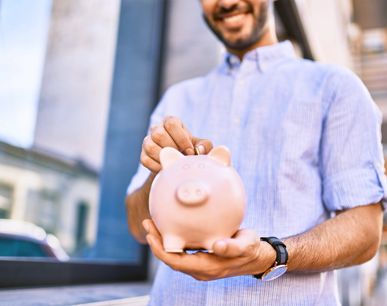 man putting money into piggy bank