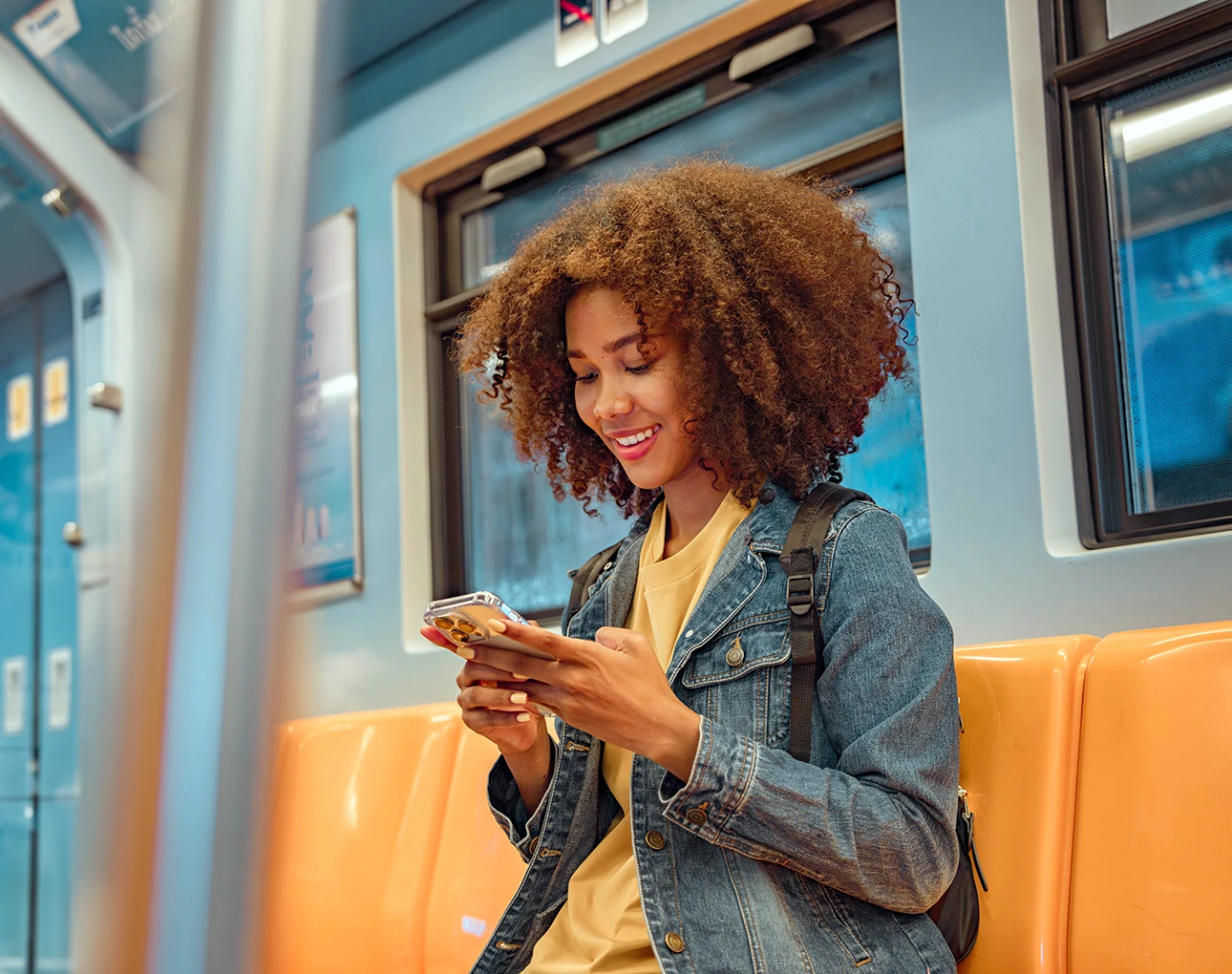 Young woman on a train smiling at her phone