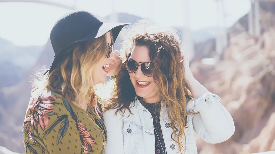 Two woman in sunglasses whispering