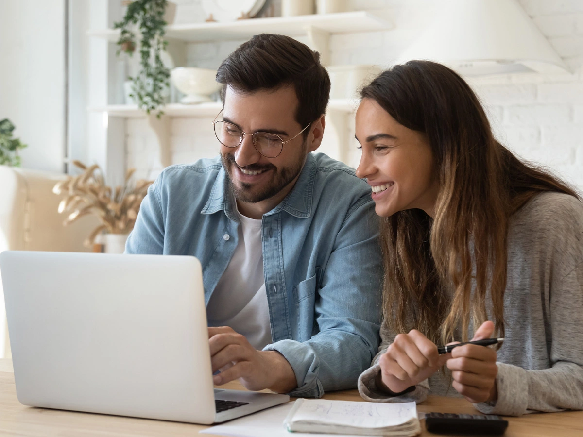 Man and woman smiling down at laptop