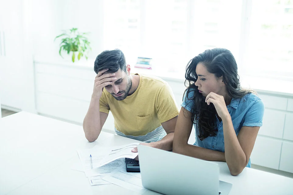 Man and woman looking at documents with a laptop concerned