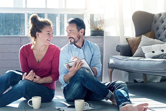 Man and woman sitting down writing in front of a couch