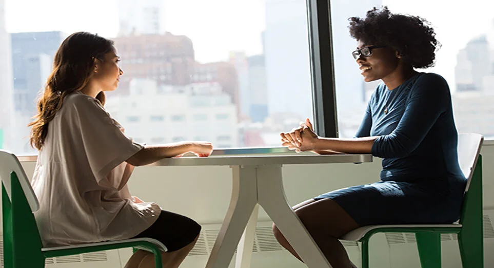 Two woman sitting at a table in a discussion
