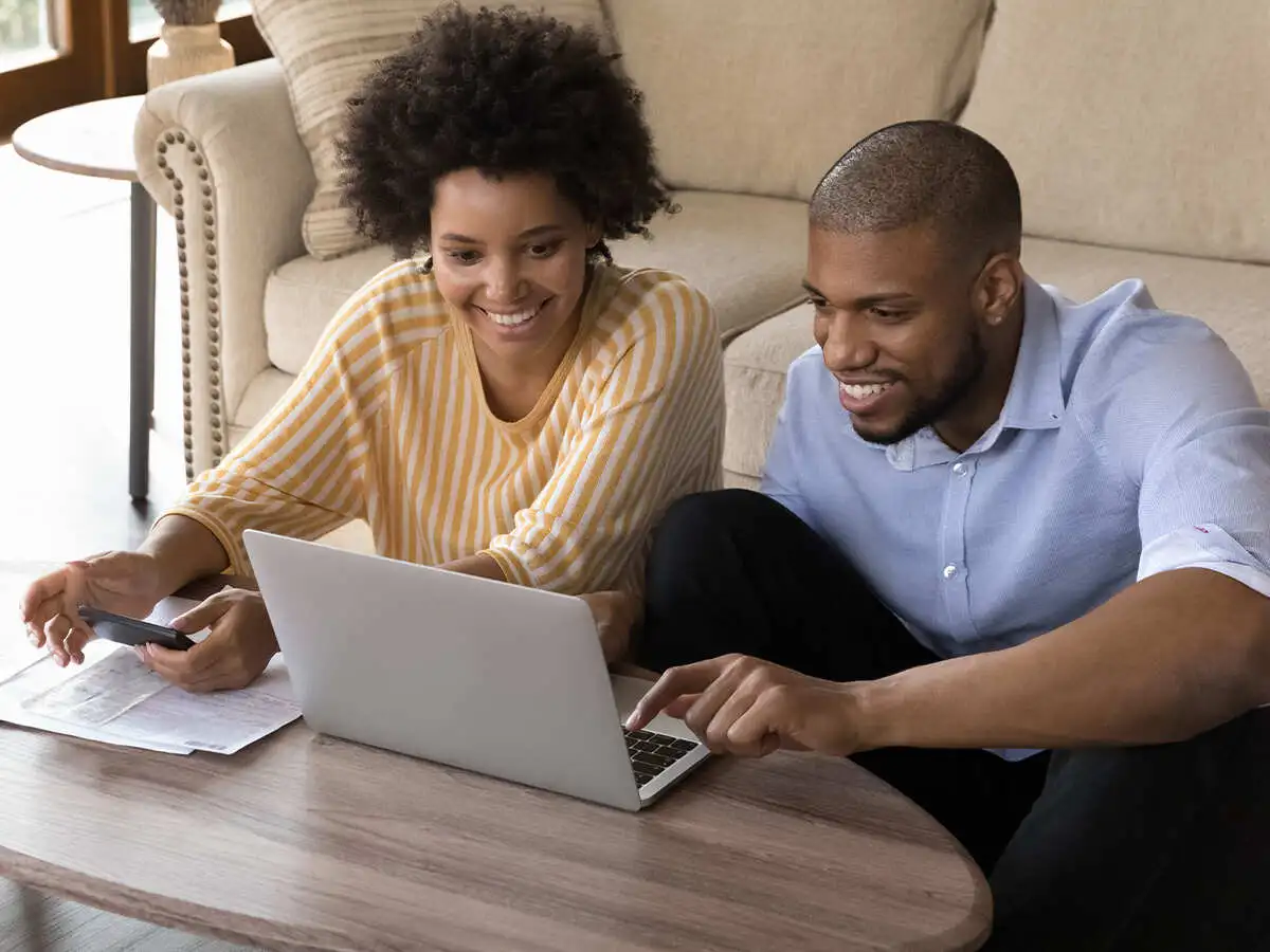 Couple looking at documents and a laptop smiling