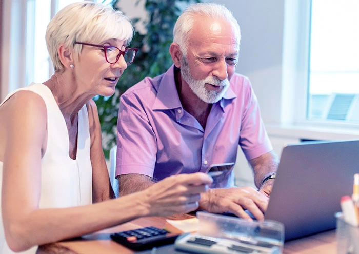 Elderly couple looking at a credit card and laptop